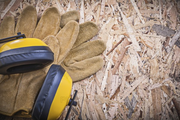 Safety leather gloves earmuffs on chipboard