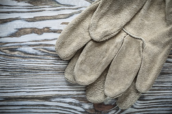 Pair of leather safety gloves on wooden board