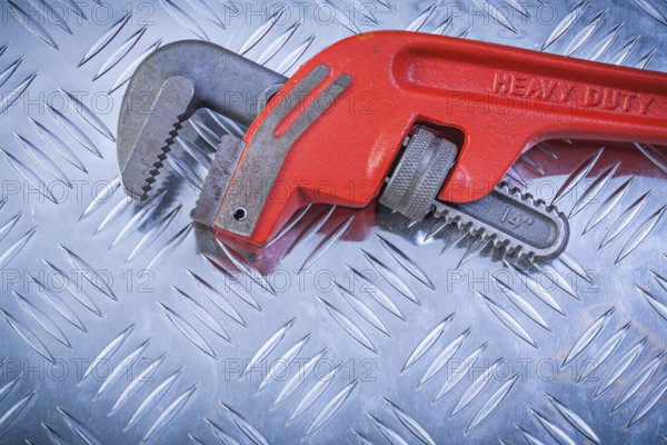 Metal monkey wrench on grooved metallic plate construction concept
