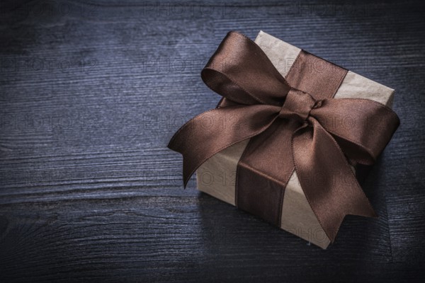 Boxed present with brown bow on vintage wood board copyspace