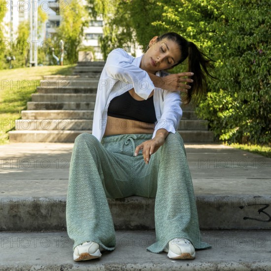 Urban dancer showcasing seated dance moves in a city park