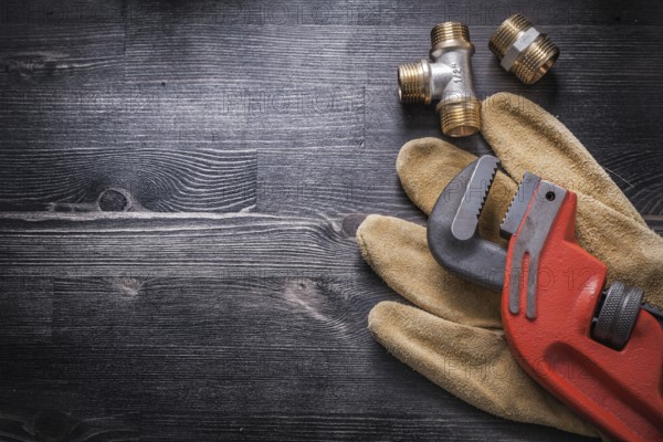 Monkey wrench brass plumbing fittings leather safety gloves construction concept