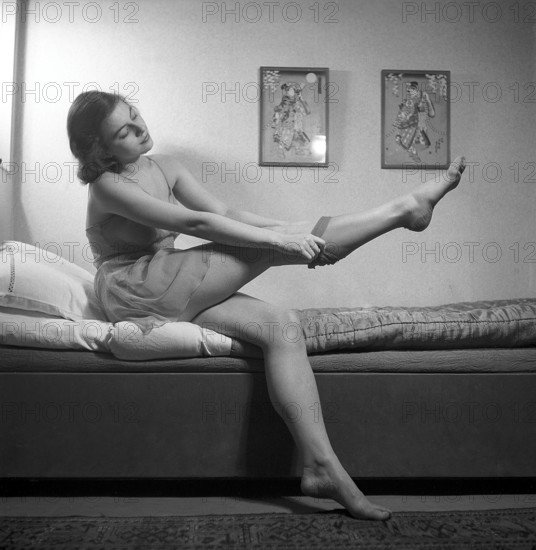 Nylon stockings in the 1940s. A young woman is getting dressed in the moring. The nylon stockings that fit her leg perfectly is the latest fashion. Sweden 1946. Photo Kristoffersson ref Y24_2-2