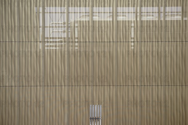 The outer façade of a combined heat and power plant made of perforated metal panels behind which pipes run