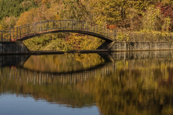 Footbridge over small pond in mountain valley with trees in beautiful fall colors in background, South Korea