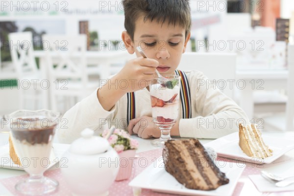 Child eat strawberry smoothie. Choco Cake on a table