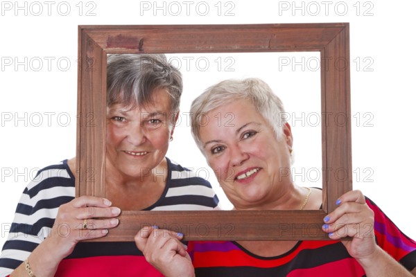 Two senior women looking through a picture frame Two senior women looking through a picture frame