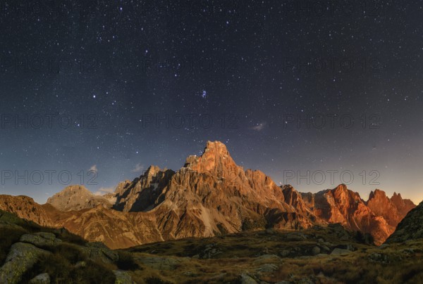 Cimon delle Pala mountain above Passo Rolle with clouds at night with stars
