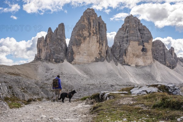 A female person hiking lonely with her dog around the Drei Zinnen mountains, the Dolomites in South Tirol