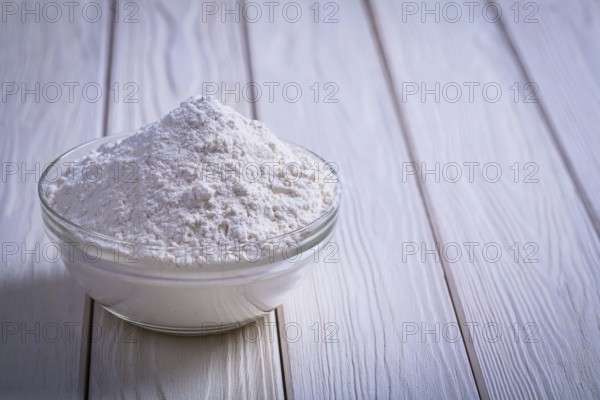 Glass bowl with flouron white painted wooden board food and drink still life