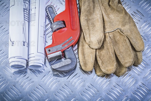 Monkey wrench construction drawings leather safety gloves on corrugated metal background building concept