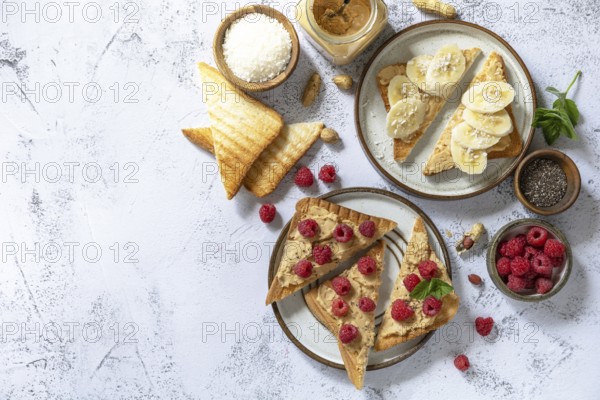 Sweet dessert sandwich breakfast. Tasty toasted with peanut butter, banana and raspberry on a gray stone table top. Top view flat lay background. Copy space