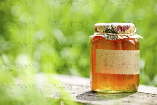 Honey jar on table against nature background