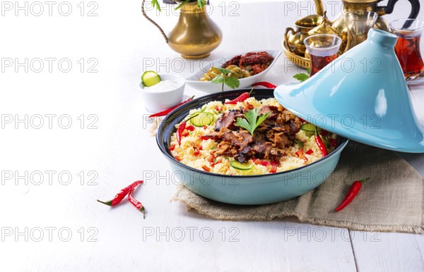 Tajin with couscous, vegetables and meat on a white background