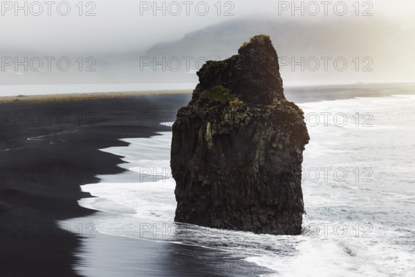 Detail of Arnardrangur rock in the middle of peninsula near Reynisfjara Beach view point Dyrholaey in overcast weather.