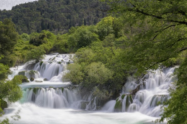 Several waterfalls flow through a lushly wooded hilly landscape, Krka Krka Waterfalls National Park, Croatia