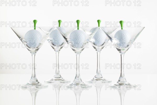 Five glasses of champagne and golf equipments on the glass desk