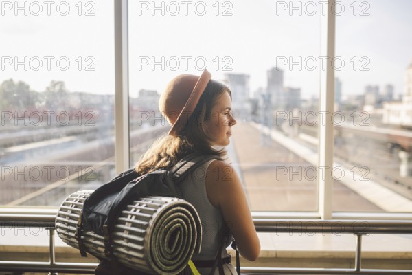 Traveler Rear view woman standing at the window in hall Train Station departure with backpack, Selective focus, Travel concept. transportation concept. Theme travel public transport