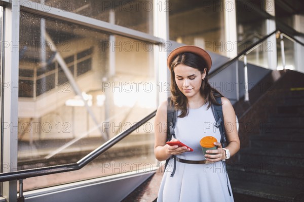 Enjoy travelling. Female waiting train on station with backpack, using smart phone. Tourist makes plan, watching schedule route railway, railroad transport concept. woman wait train on railway station
