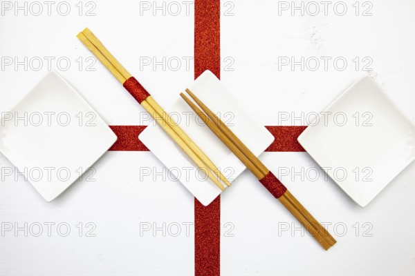 Ceramic bowls and bamboo chopsticks for sushi food with red and white decoration