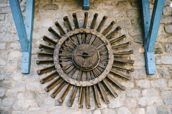 The wheel of a water mill. The old wooden wheel of the water mill is used as an element of decor on the wall