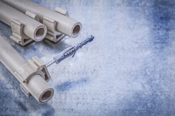 Plastic water pipe clamps on metallic background construction concept