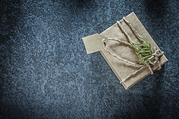 Wrapped gift box with thuya branch on black background holidays concept