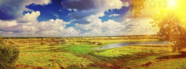 Panoramic view on big meadow with small flood sky with sun instagram stile