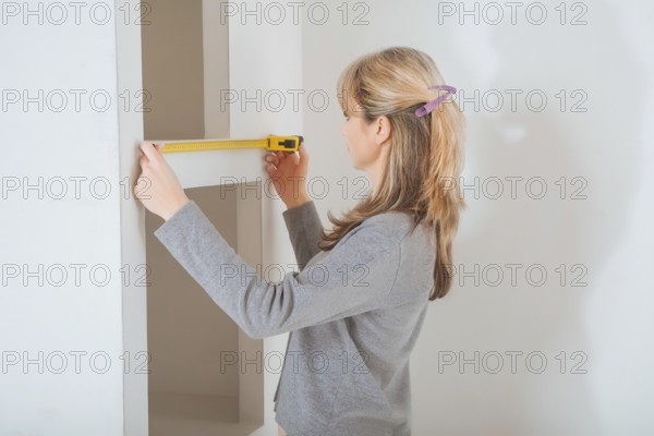 Female worker measuring with tape measure