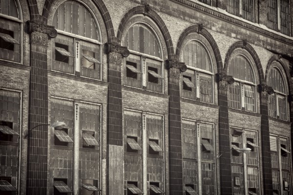 Old power plant - windows and brick walls with sandstone decoration, sepia toned black and white image