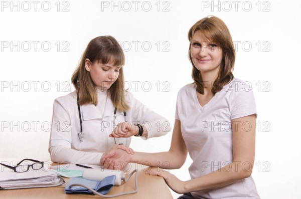 Physician considers the pulse of the girl at the desk in the office