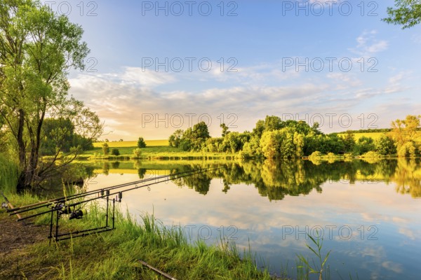 Fishing rods on a riverbank of calm river at sunset