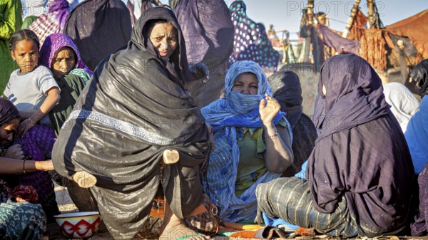 Gathering of people in colourful, traditional clothing in a desert landscape, woman at the traditional Tuareg festival of Tamanrasset in the Sahara in Algeria