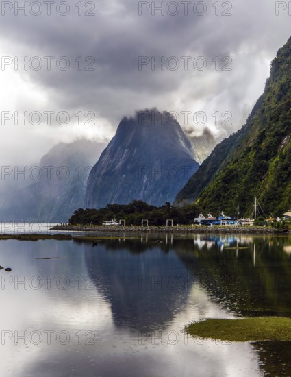 New Zealand. Storm clouds cover the sky over the famous ocean fjord Milford Sound. Port of tourist and pleasure ships, yachts and boats. Concept of active and photographic tourism