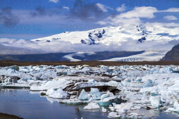 Clear and cold day in July. Arctic Circle. White and blue icebergs and ice floes reflected in the water. Iceland. The lagoon Jokulsaurloun. The concept of extreme, northern and photo tourism