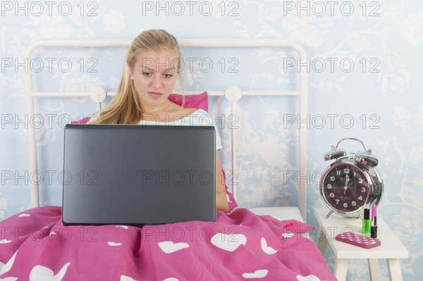 Teen girl with laptop in bed