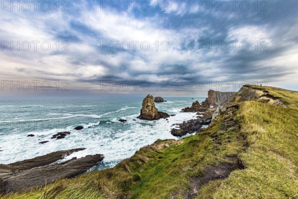 Portio beach. Rocky coastline of the Atlantic Ocean. Spanish coast, Cantabria. Stormy autumn day in the Bay of Biscay. Picturesque cliffs and huge stones oppose the ocean