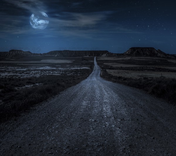 Moon, stars and clouds in the night. Wild west road illuminated from the moon. Moonlight and road background. Dark blue backdrop