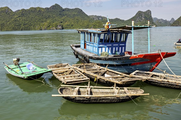 Fishing boats float peacefully on green waters surrounded by steep, forested hills, fishermen and fishing boats in Halong Bay, Vietnam