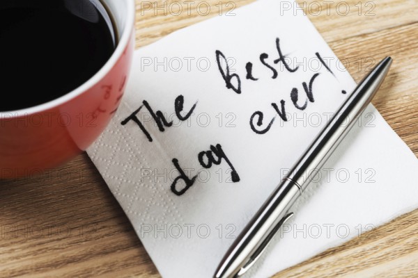 Coffee cup pen and napkin with words on wooden table