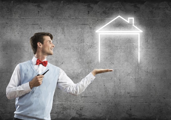 Confident and young businessman smoking pipe and drawn house on gray wall background