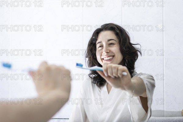 Portrait of a pretty young latin girl holding a toothbrush and smiling in front of the mirror. having proper oral hygiene makes you feel happier