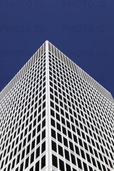 White tower block rises into the blue sky
