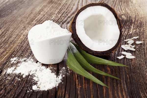 Fresh coconut half on wooden table with coconut flour. Healthy flour eating