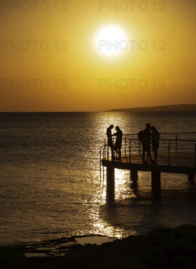 Silhouette of young couple enjoying beautiful sunset at the beach. Romantic moment human relationship at shore