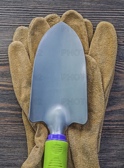 Hand spade leather safety gloves on wooden board agriculture concept