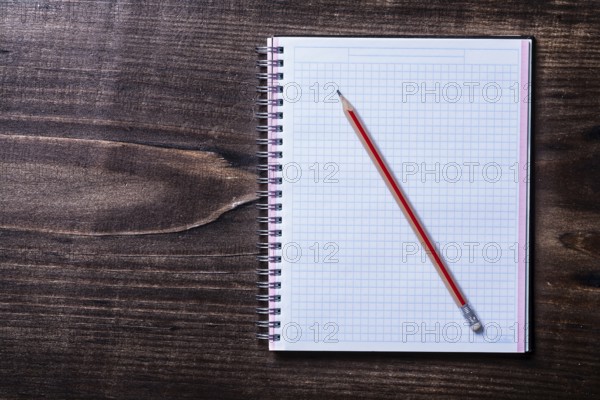 Pencil and checked copybook on wooden board education concept