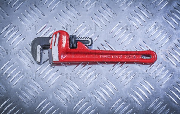 Pipe wrench on fluted metal plate construction concept