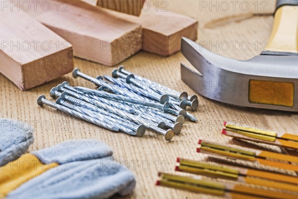 Close up view on set of carpentry tools hammer nails glove meter planks on wooden board