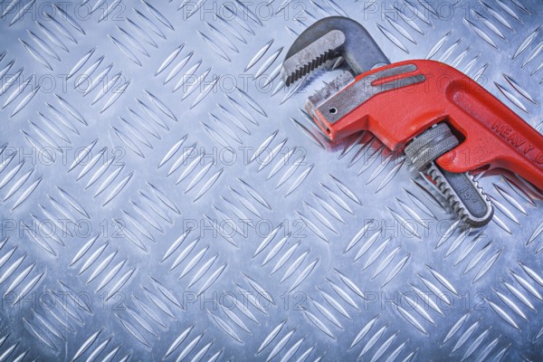 Metal pipe wrench on channeled metallic sheet maintenance concept